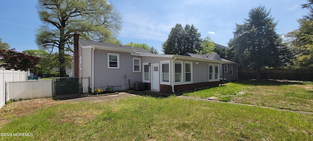 rear view of house with central air condition unit and a lawn