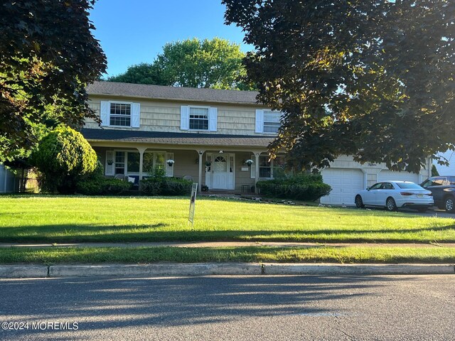 view of front property with a garage, a front yard, and a porch