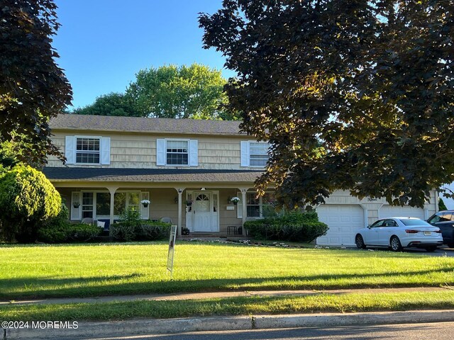 view of front of house with covered porch, a garage, and a front lawn