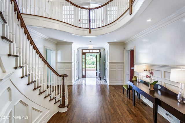 entrance foyer featuring dark wood-type flooring, a towering ceiling, and crown molding