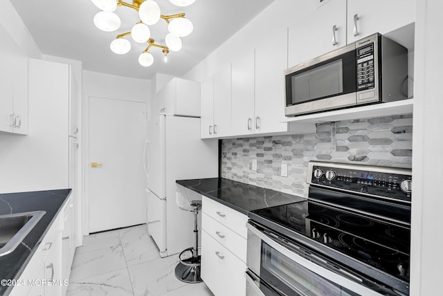 kitchen featuring white cabinetry, sink, backsplash, stainless steel appliances, and an inviting chandelier