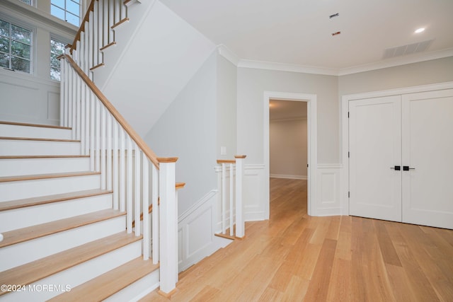 stairs featuring crown molding and hardwood / wood-style floors