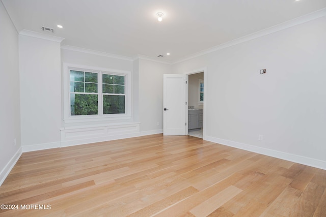 spare room with crown molding and light wood-type flooring