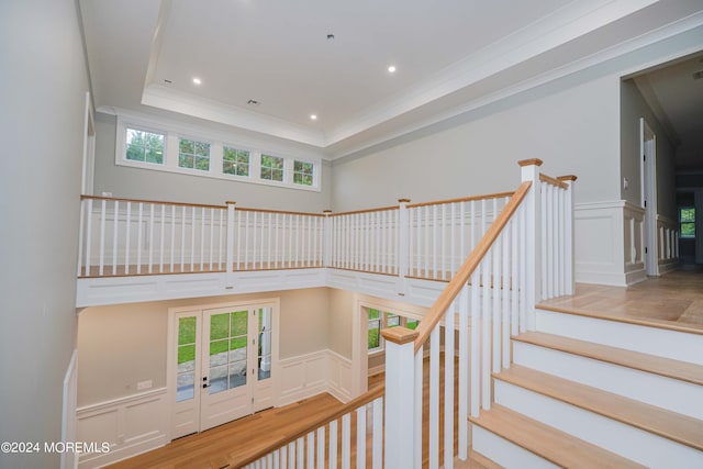 stairway with hardwood / wood-style flooring, a tray ceiling, and crown molding