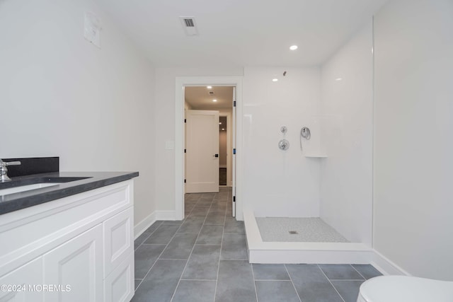 bathroom with vanity, a shower, toilet, and tile patterned floors