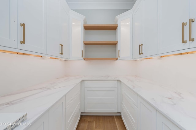 kitchen featuring wood-type flooring, white cabinets, and light stone countertops