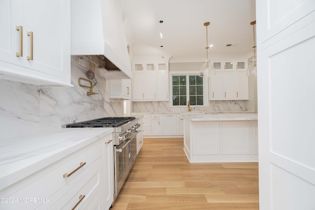 kitchen with double oven range, backsplash, light hardwood / wood-style flooring, and white cabinetry