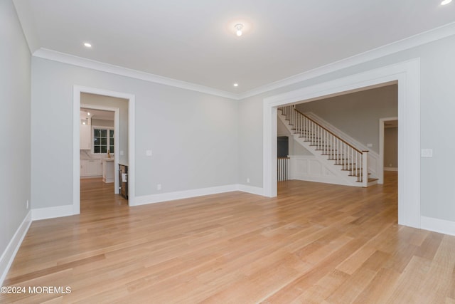 spare room with light wood-type flooring and crown molding