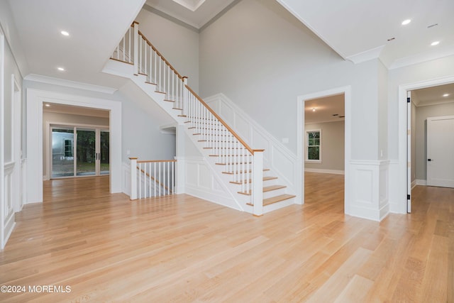 stairs with wood-type flooring and ornamental molding