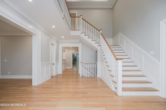 staircase featuring wood-type flooring and ornamental molding