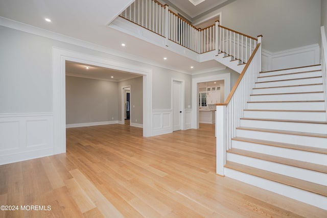 stairway with ornamental molding and hardwood / wood-style floors