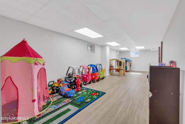 playroom with hardwood / wood-style flooring and a paneled ceiling