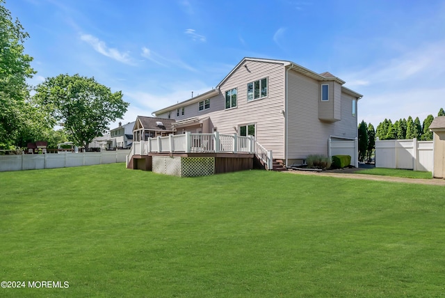 rear view of house featuring a garage, a lawn, and a wooden deck