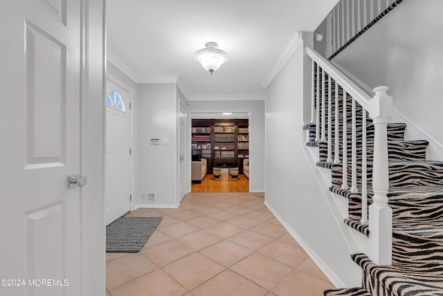 tiled foyer entrance with crown molding