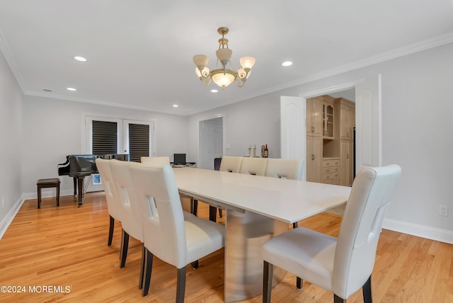 dining area with light hardwood / wood-style flooring, crown molding, and a chandelier