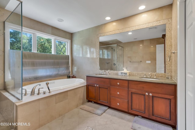 bathroom with tile patterned flooring, vanity, tile walls, and shower with separate bathtub