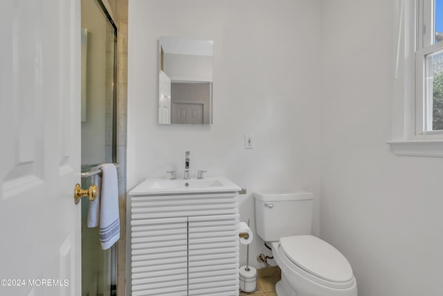 bathroom with tile patterned floors, vanity, toilet, and a shower with shower door