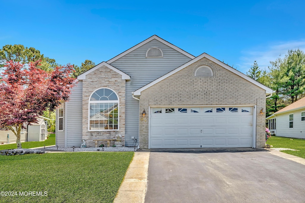 64 Canterbury Ln, Toms River, NJ 08757 - traditional-style house with stone siding, an attached garage, a front yard, and aphalt driveway