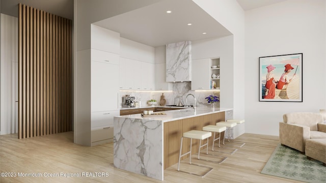 390 Ocean Ave Unit 2312, Long Branch, NJ 07740 - kitchen featuring a peninsula, modern cabinets, light wood finished floors, a kitchen bar, and white cabinetry