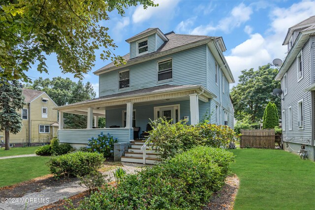 view of front of home with covered porch and a front lawn