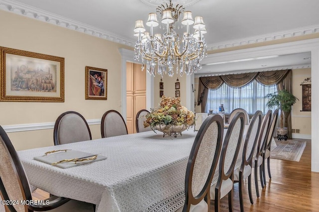 dining area with hardwood / wood-style floors, a notable chandelier, and crown molding