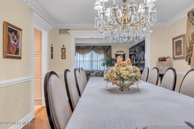 dining room with hardwood / wood-style flooring, an inviting chandelier, and ornamental molding