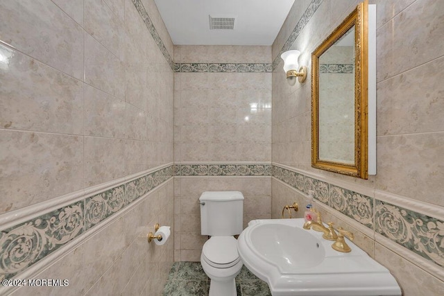 bathroom featuring sink, toilet, and tile walls