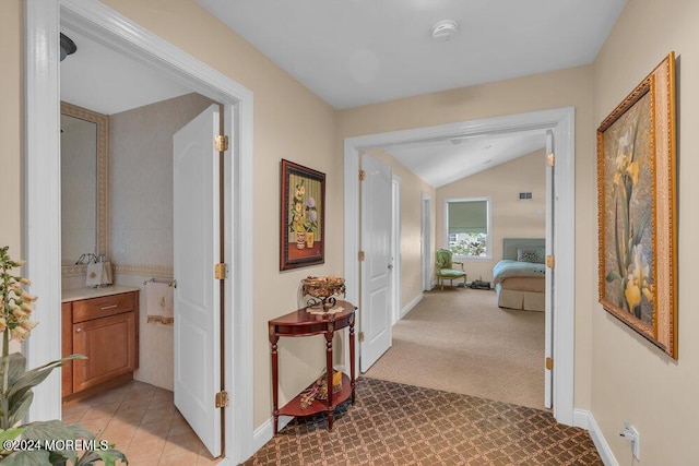 corridor with light colored carpet and lofted ceiling