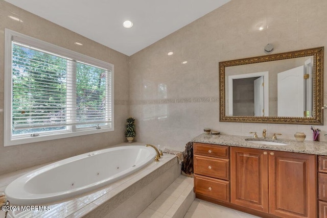 bathroom with vanity, tiled bath, vaulted ceiling, and tile walls