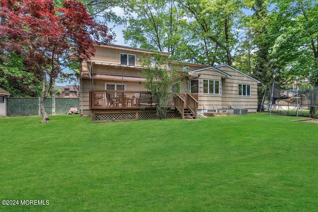 rear view of property with a yard, a trampoline, a deck, and central air condition unit