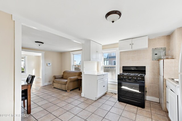 107 18th Ave, Belmar, NJ 07719 - kitchen with black gas range oven, light tile patterned floors, white cabinetry, and plenty of natural light