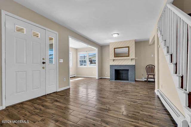 foyer entrance with a fireplace, dark hardwood / wood-style floors, and baseboard heating