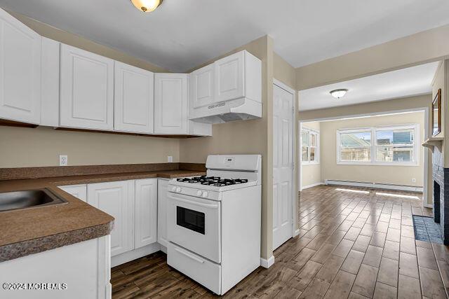 kitchen with a baseboard heating unit, white cabinetry, white range with gas cooktop, and dark wood-type flooring