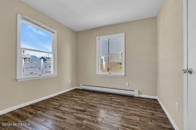 spare room with dark hardwood / wood-style flooring and baseboard heating