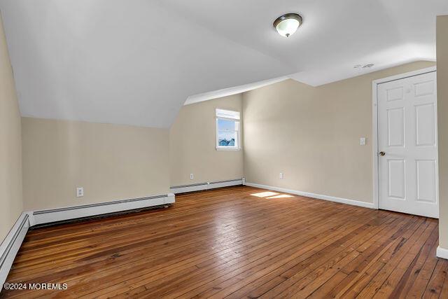 bonus room with vaulted ceiling, dark hardwood / wood-style flooring, and a baseboard radiator