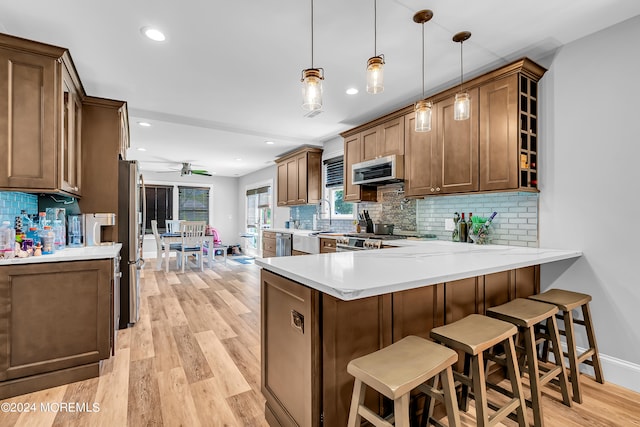 kitchen featuring hanging light fixtures, backsplash, and light wood-type flooring