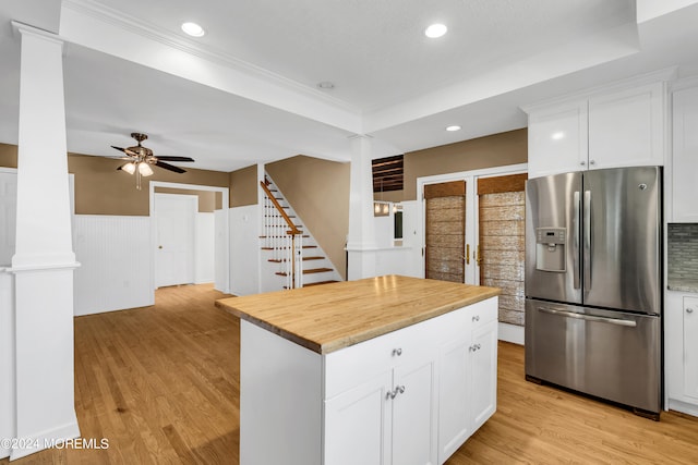 kitchen with stainless steel refrigerator with ice dispenser, light hardwood / wood-style floors, a kitchen island, ceiling fan, and a tray ceiling