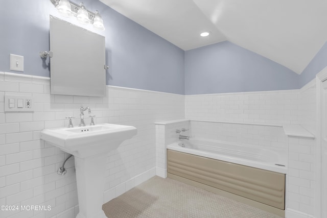 bathroom featuring backsplash, tile walls, a bath, and lofted ceiling