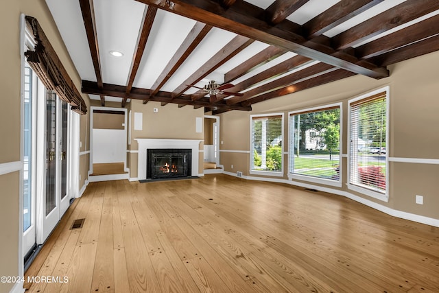 unfurnished living room featuring a premium fireplace, beam ceiling, light hardwood / wood-style floors, and ceiling fan