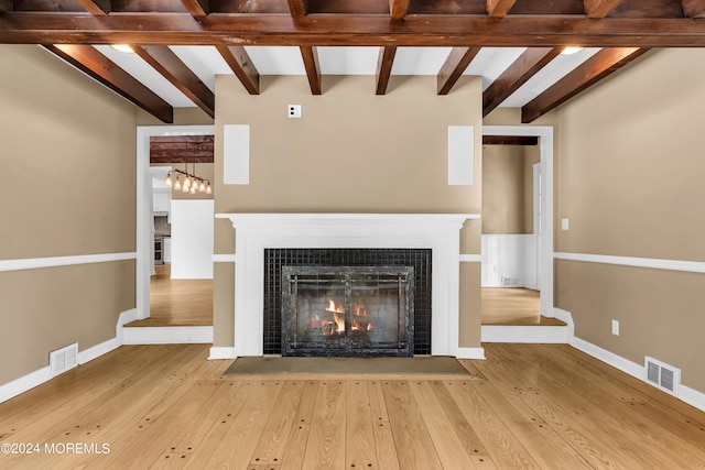 unfurnished living room with beam ceiling, hardwood / wood-style flooring, and a tiled fireplace