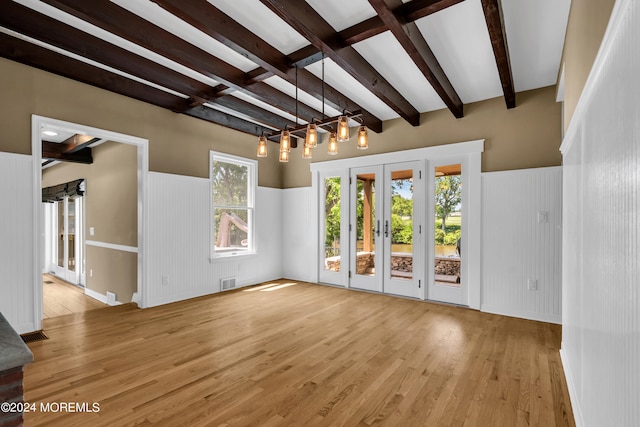 empty room featuring beam ceiling, french doors, and light hardwood / wood-style flooring