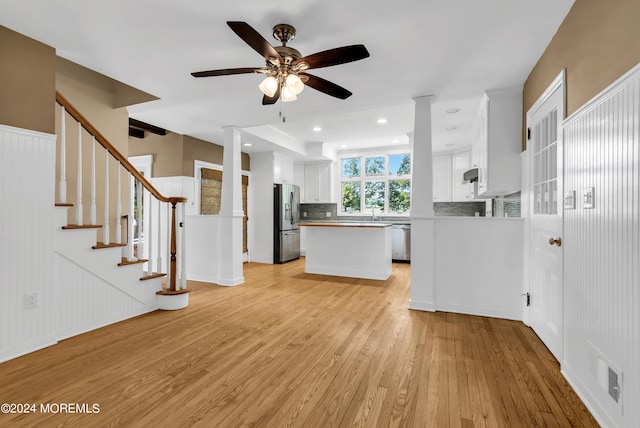 kitchen with stainless steel appliances, light hardwood / wood-style flooring, backsplash, and white cabinetry