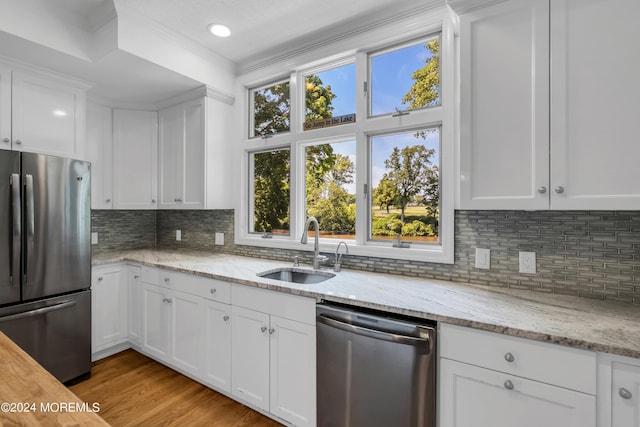 kitchen with light wood-type flooring, stainless steel appliances, white cabinets, backsplash, and sink