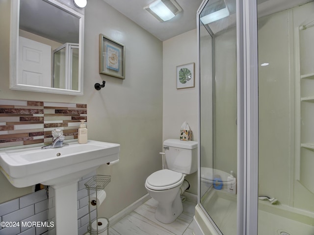 bathroom featuring a shower with door and toilet