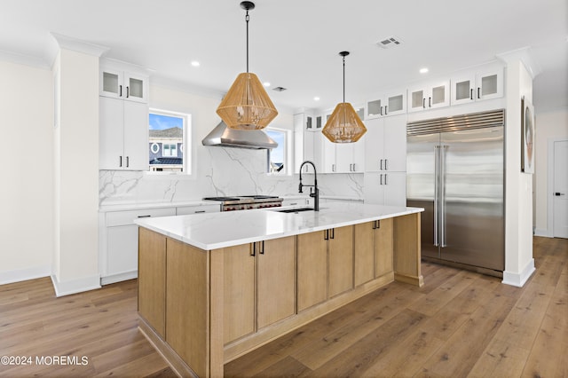 kitchen featuring white cabinets, light hardwood / wood-style floors, a spacious island, and appliances with stainless steel finishes