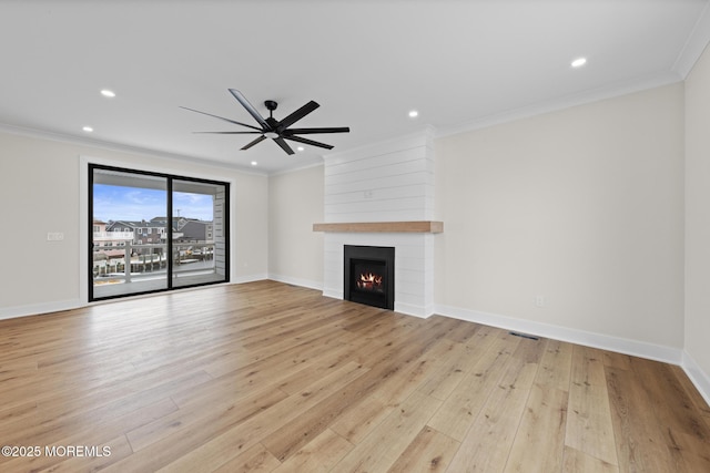 unfurnished living room featuring light hardwood / wood-style flooring, ceiling fan, ornamental molding, and a fireplace