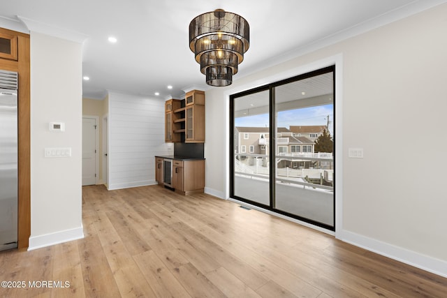 unfurnished living room with a notable chandelier, ornamental molding, light hardwood / wood-style floors, and beverage cooler