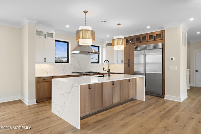 kitchen with a kitchen island with sink, hanging light fixtures, sink, appliances with stainless steel finishes, and white cabinets