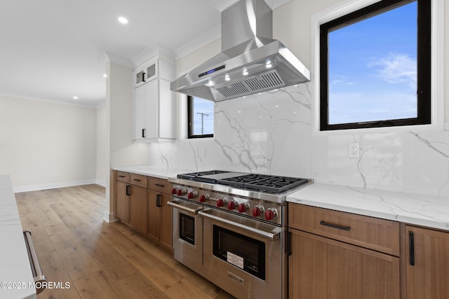 kitchen featuring light hardwood / wood-style flooring, double oven range, exhaust hood, white cabinets, and crown molding