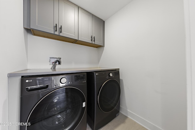 clothes washing area with washer and dryer and cabinets